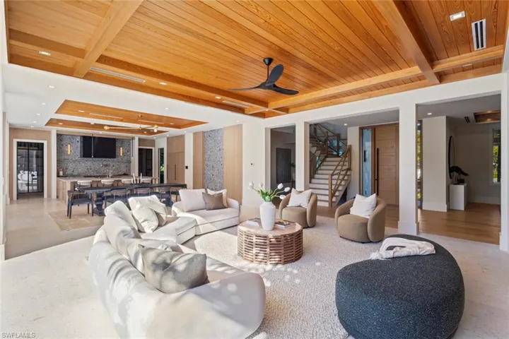 Living area with a raised ceiling, stairway, a wood ceiling with exposed beams, recessed lighting, and a ceiling fan