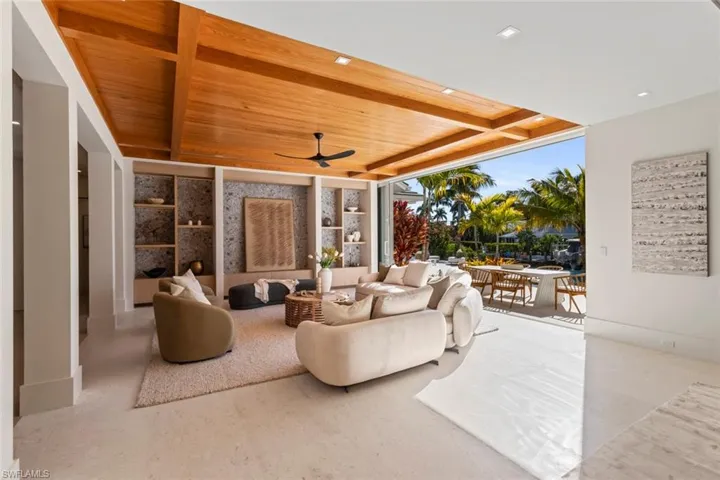 Living area with floor to ceiling windows, ceiling fan, and a wooden ceiling with exposed beams