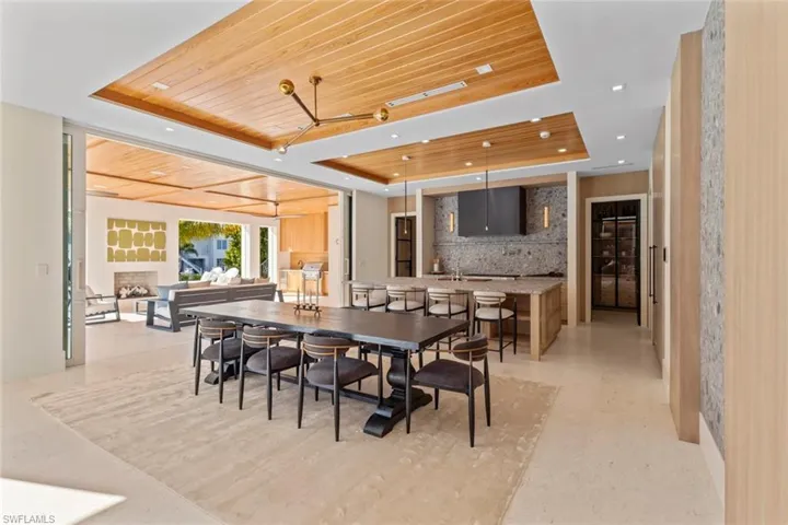 Dining room with a tray ceiling, wooden ceiling, a fireplace, and recessed lighting