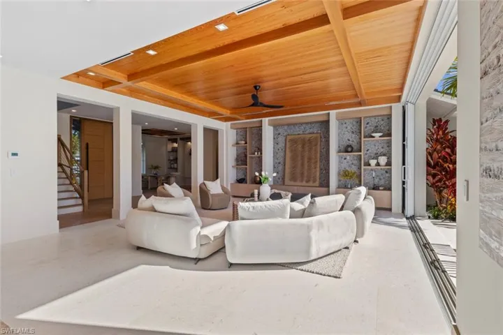 Living area with a wood ceiling with exposed beams, stairway, and ceiling fan