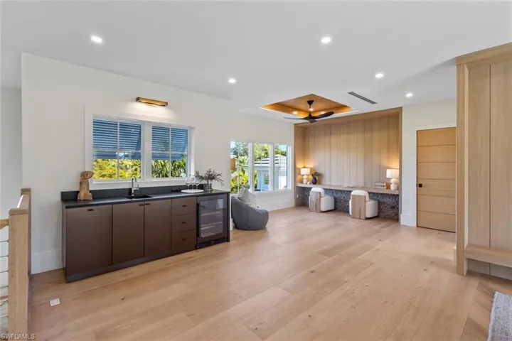 Kitchen with recessed lighting, wine cooler, dark countertops, light wood-style flooring, and dark brown cabinetry