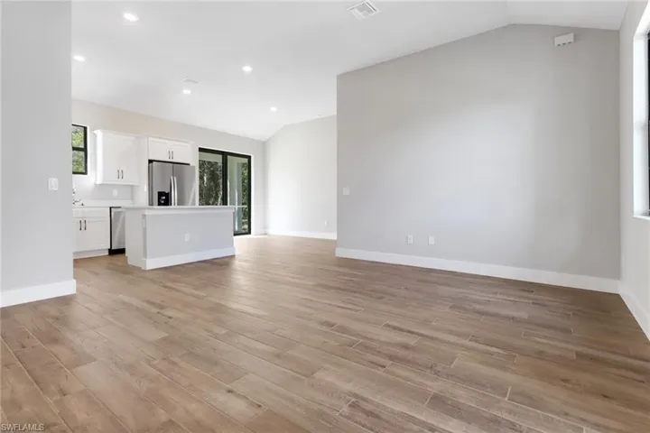 Unfurnished living room with vaulted ceiling and light wood-type flooring