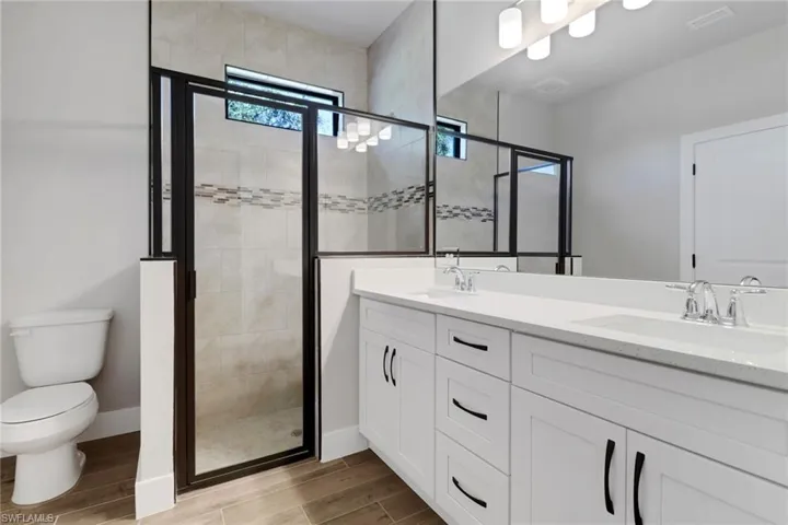 Bathroom with an enclosed shower, vanity, and toilet
