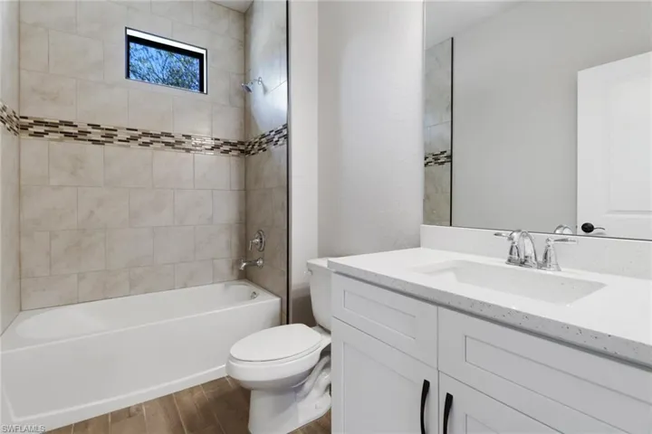 Full bathroom with tiled shower / bath, wood-type flooring, toilet, and vanity