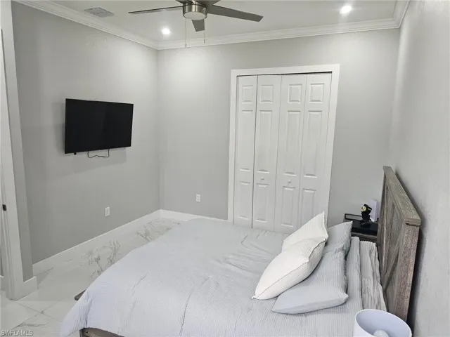 Bedroom with ornamental molding, ceiling fan, and a closet