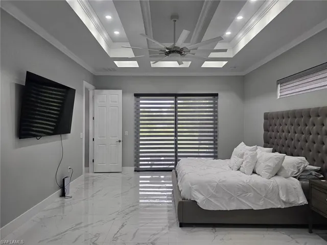 Bedroom with crown molding, ceiling fan, and a tray ceiling