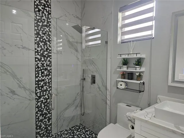Bathroom with vanity, toilet, and a shower with shower door