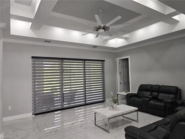 Living room featuring coffered ceiling, ceiling fan, beam ceiling, and crown molding
