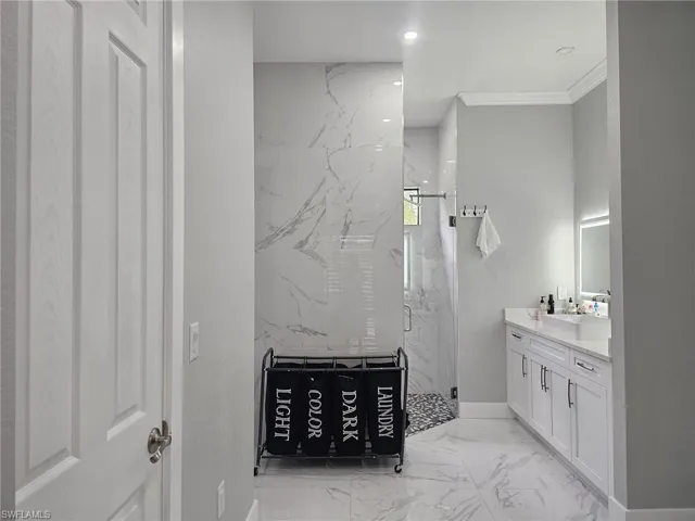 Bathroom with ornamental molding, vanity, and walk in shower
