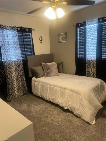 Carpeted bedroom featuring ceiling fan