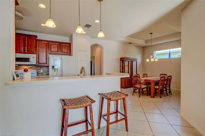 Kitchen, tray ceiling, backsplash, white appliances, and light tile patterned floor