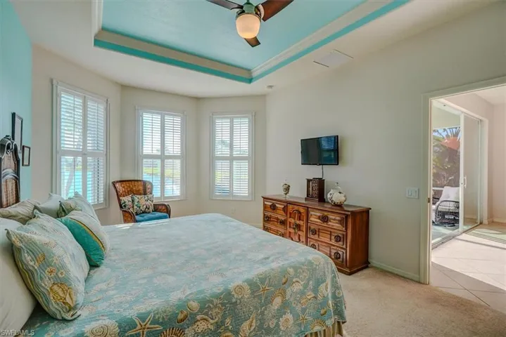Master Bedroom featuring, ceiling fan, light colored carpet, a tray ceiling crown molding