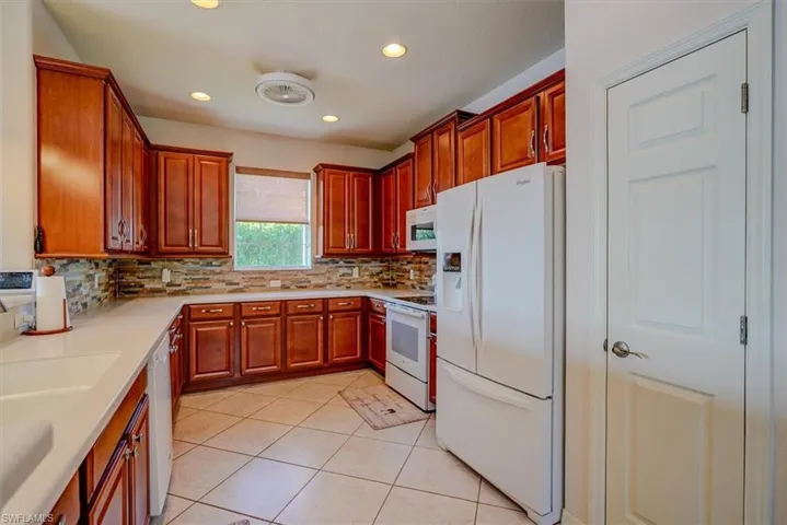 Kitchen with recessed lighting, white appliances, Corian countertops, decorative backsplash