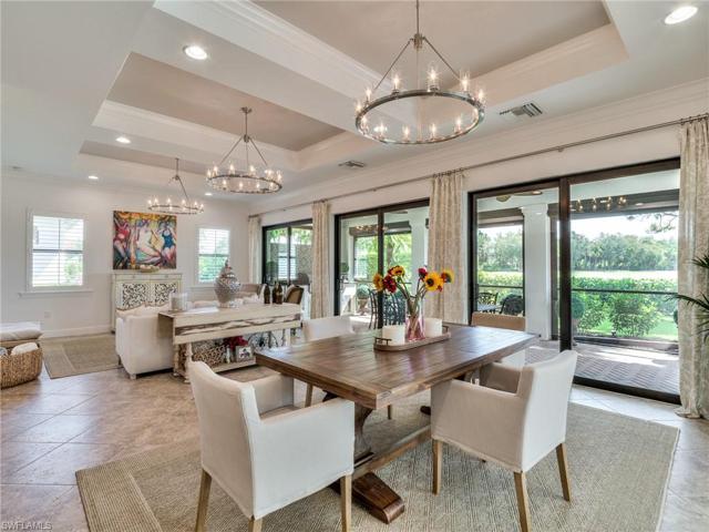 Great room with coffered ceiling, new chandeliers 2023, and multiple sliders to covered outdoor kitchen/dining