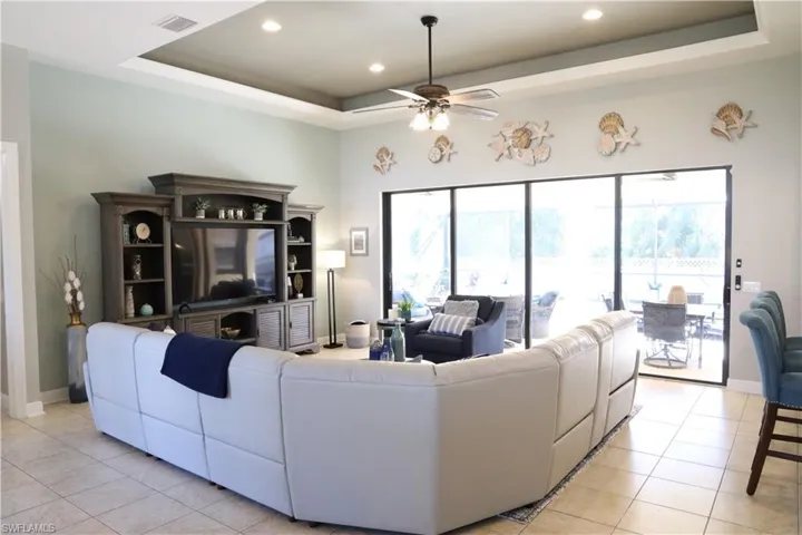 Tiled living room with ceiling fan and a raised ceiling