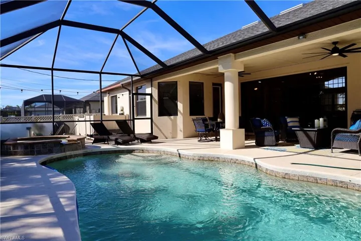 View of pool featuring ceiling fan, a patio area, an in ground hot tub, and glass enclosure