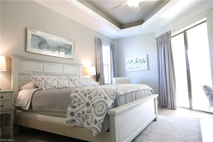 Bedroom with access to exterior, a raised ceiling, and ceiling fan