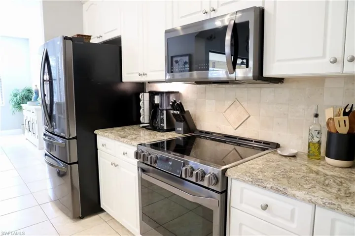 Kitchen with white cabinets, decorative backsplash, and appliances with stainless steel finishes