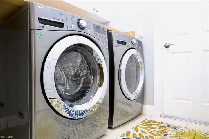 Clothes washing area with separate washer and dryer and light tile patterned floors