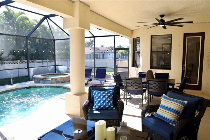 View of swimming pool featuring an in ground hot tub, a patio, glass enclosure, and ceiling fan