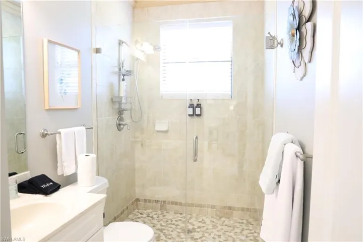 Bathroom featuring toilet, an enclosed shower, and vanity