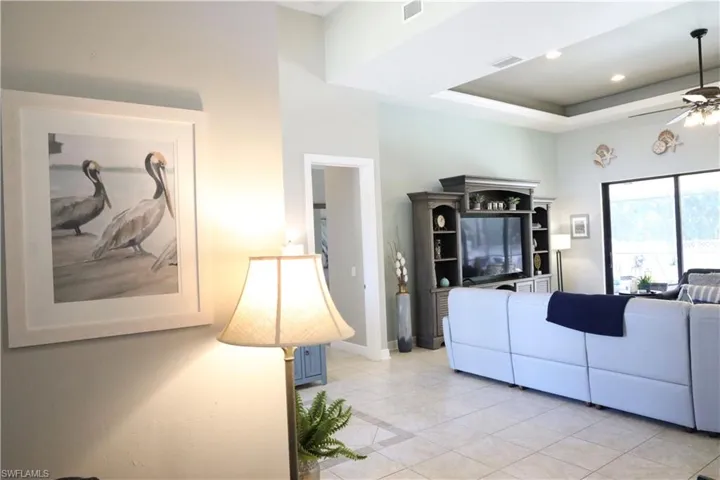 Tiled living room with a raised ceiling and ceiling fan