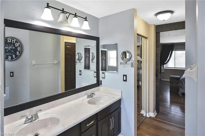 Full bath with double vanity and dark wood finished floors