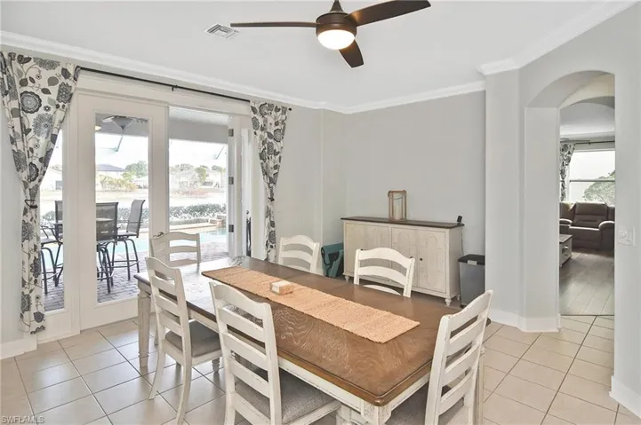 Dining space featuring a ceiling fan, crown molding, plenty of natural light, arched walkways, and light tile patterned floors