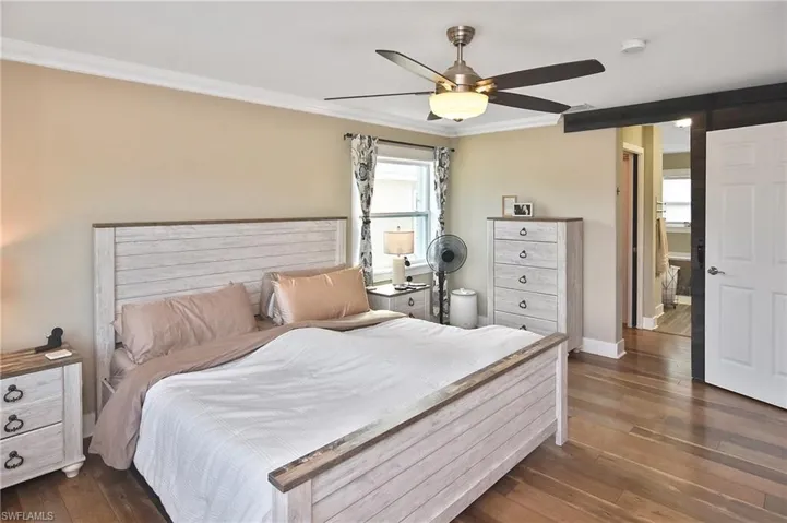 Bedroom with crown molding, ceiling fan, and dark wood-style floors