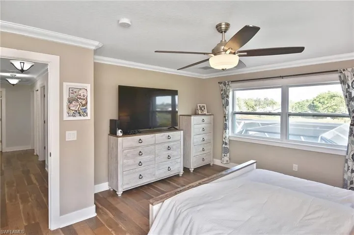 Bedroom featuring dark wood-style floors, ornamental molding, and a ceiling fan