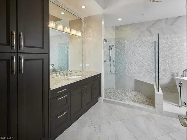 Bathroom featuring tile patterned floors, vanity, and a tile shower