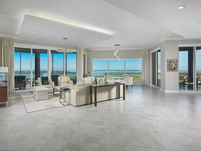 Living room with ornamental molding, a water view, plenty of natural light, and a chandelier