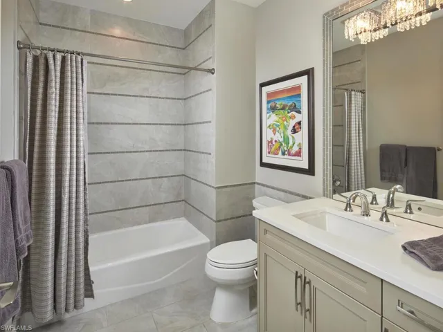 Full bathroom featuring shower / tub combo with curtain, tile patterned flooring, vanity, a notable chandelier, and toilet