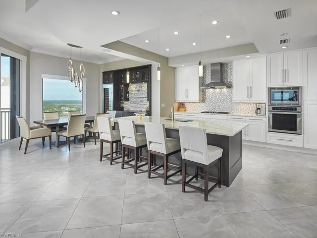 Kitchen featuring white cabinetry, appliances with stainless steel finishes, pendant lighting, and wall chimney range hood