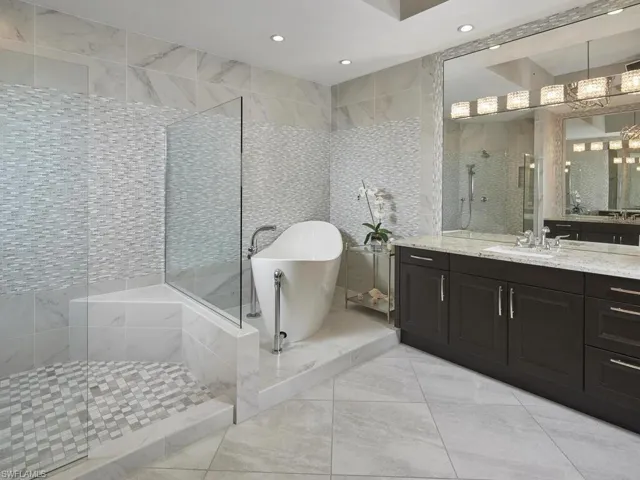 Bathroom featuring an inviting chandelier, vanity, separate shower and tub, and tile walls
