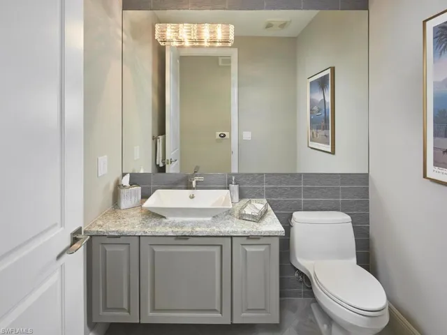 Bathroom with vanity, tile walls, and toilet