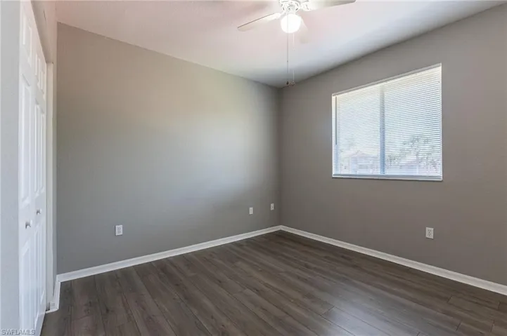 Empty room featuring dark wood finished floors, a ceiling fan, and baseboards