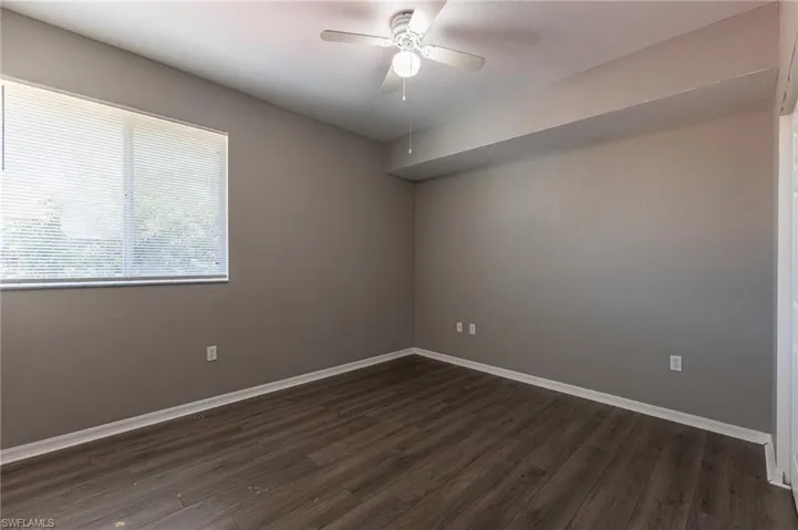 Spare room with ceiling fan, dark wood-style flooring, and baseboards