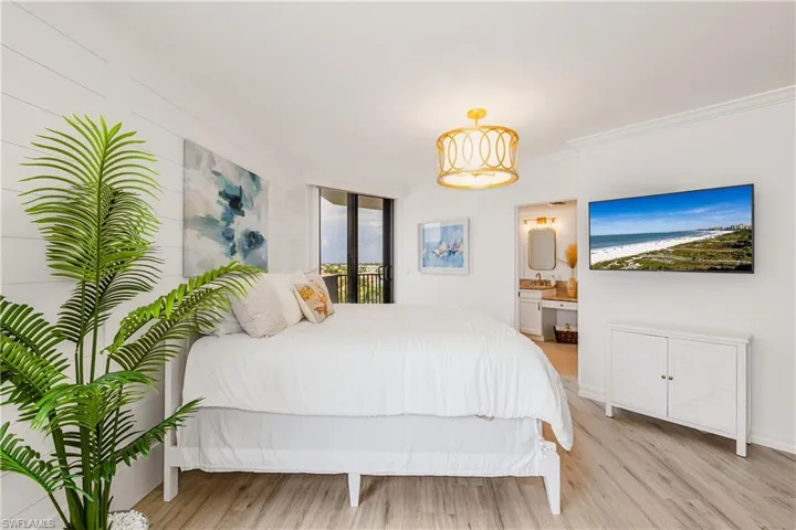 Bedroom featuring ensuite bath, ornamental molding, and light hardwood / wood-style floors