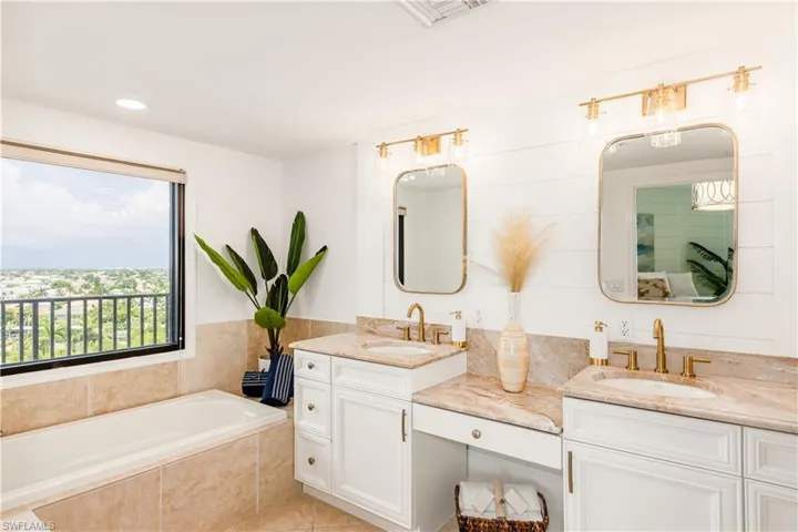 Bathroom with tiled tub, vanity, and tile patterned floors