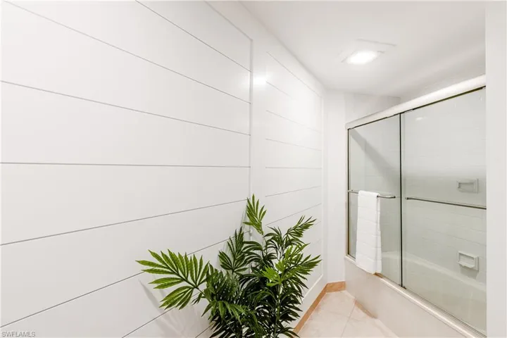 Bathroom with tile patterned floors and enclosed tub / shower combo