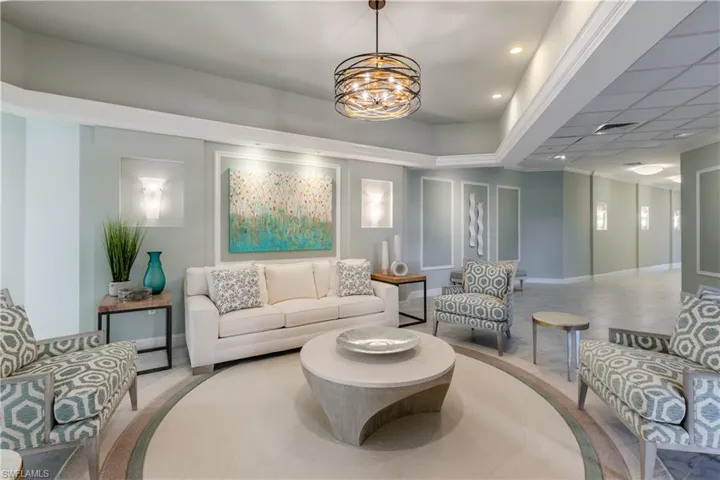 Tiled living room featuring an inviting chandelier and a drop ceiling