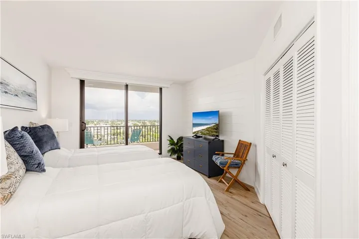 Bedroom featuring access to exterior, wood walls, a closet, and light hardwood / wood-style floors