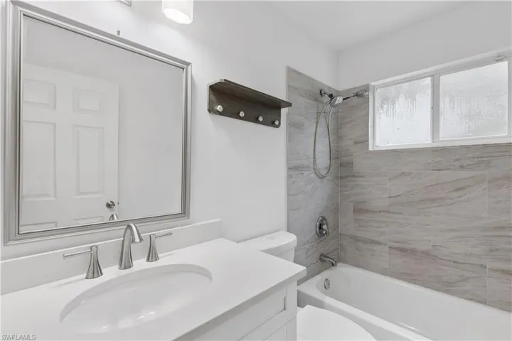 Full bathroom featuring vanity, tiled shower / bath combo, and toilet