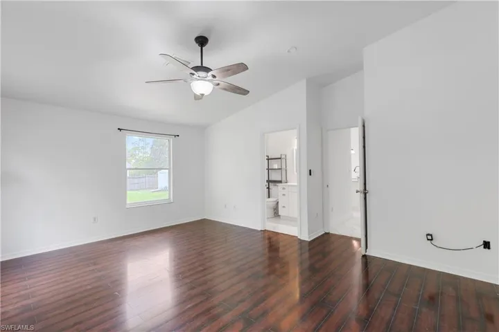 Empty room featuring lofted ceiling, ceiling fan, and dark hardwood / wood-style floors