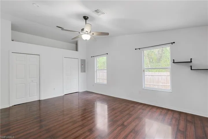Empty room with ceiling fan, vaulted ceiling, dark wood-type flooring, and a healthy amount of sunlight