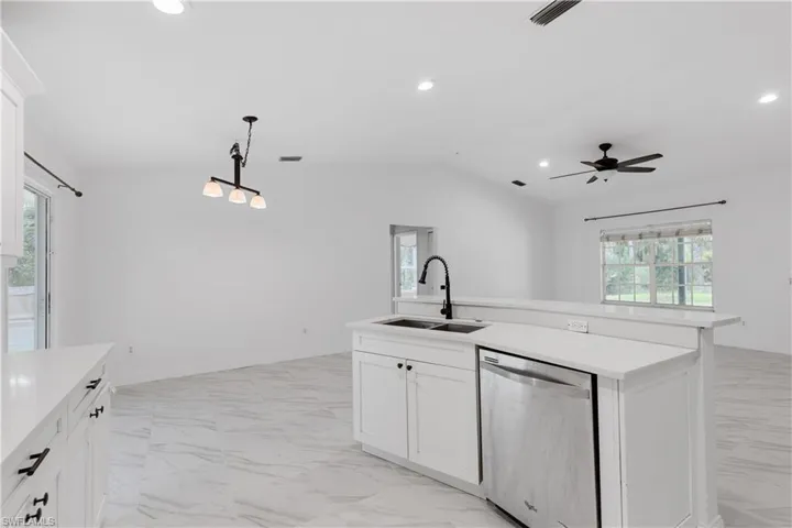 Kitchen featuring lofted ceiling, white cabinetry, dishwasher, and sink