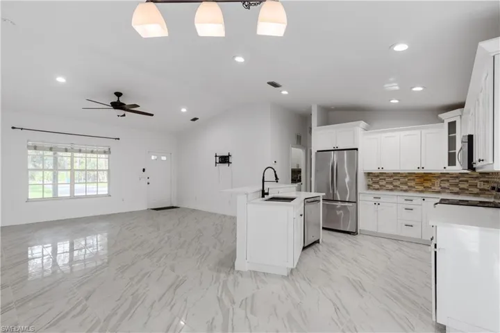 Kitchen featuring sink, white cabinets, lofted ceiling, stainless steel appliances, and ceiling fan