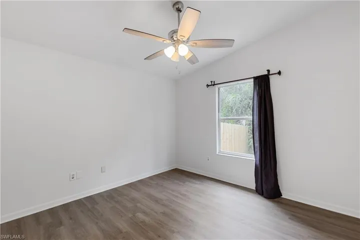 Empty room featuring light wood-type flooring, lofted ceiling, and ceiling fan
