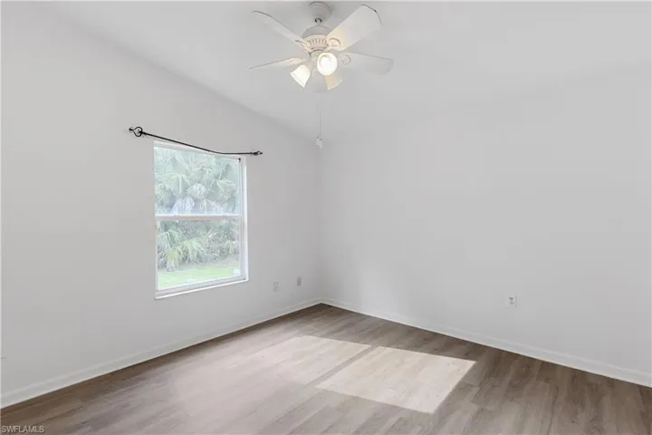 Empty room with lofted ceiling, ceiling fan, and light hardwood / wood-style flooring
